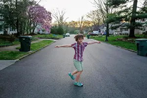 8 10 Years Old Prints: A happy child spins with his arms out in a street at sunset in Spring