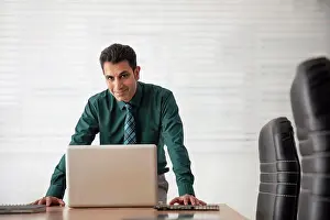 Determined Prints: A HAPPY CORPORATE PROFESSIONAL LOOKING AT CAMERA WHILE STANDING IN A CONFERENCE ROOM