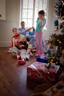 Verticals Prints: Happy family opening presents together under the Christmas tree
