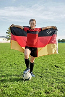 Activewear Prints: Happy girl standing with soccer ball and holding German flag on field