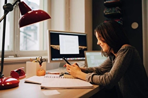 Using Phone Prints: Happy girl using mobile phone while sitting at illuminated desk