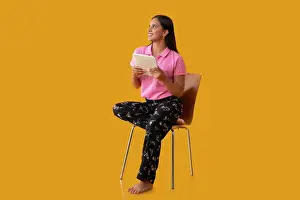 Smart Prints: Happy Indian girl looking away while sitting on chair with holding tablet in her hand