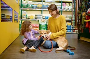 Decision Prints: Happy mother and daughter choosing new leash for their corgi dog