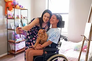 Disability Prints: Happy mother and disabled daughter with dog taking selfie at home