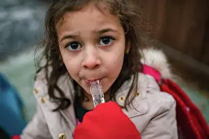 Facial Expression Prints: Happy preschool girl eating icicle with mittens