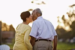 50 To 55 Years Prints: Happy senior couple kissing while standing together in the back yard