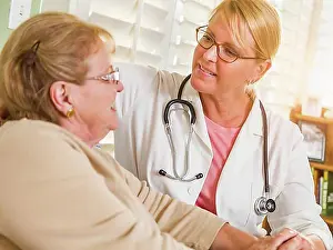 Doctors Prints: Happy smiling doctor or nurse talking to senior woman in chair at home