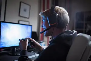 Gaming Prints: Happy teenage boy with headset playing video game at computer