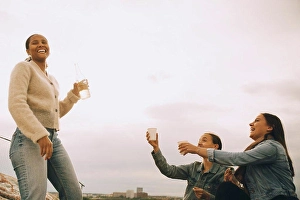 Frgbild Prints: Happy woman giving drink to female friends against sky during picnic