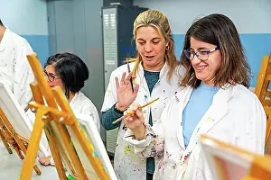 Thirty Prints: Happy woman with special needs painting in a canvas next to a teacher in the art class
