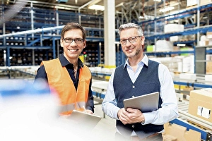 Business And Occupation Prints: Happy worker standing by manager holding tablet PC in warehouse