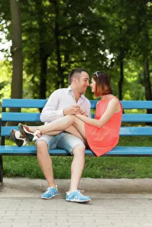 2016 Prints: Happy young couple cuddling sitting on a bench in a city park