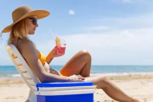 Bikini Prints: Happy young european girl drinks a cocktail and rests in a sun lounger on the beach