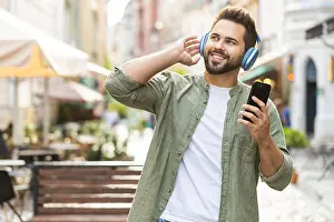 Good Prints: Happy young man in wireless headphones choosing