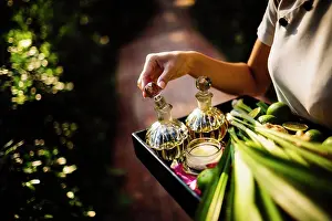 Luxury Prints: High angle close up of woman holding tray with glass bottles, candles and fruit