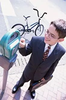 Business Suit Prints: High angle view of a boy wearing a business suit operating a parking meter