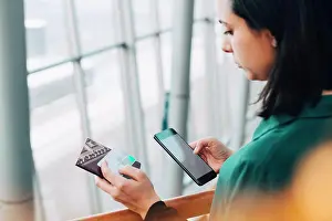 Using Phone Prints: High angle view of businesswoman holding credit card while using mobile phone in airport