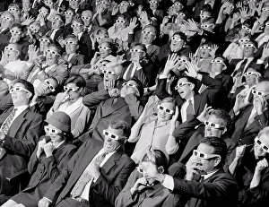 Shock Prints: High angle view of group of spectators sitting in a movie theater wearing 3-D glasses