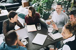 Arbetsplats Prints: High angle view of happy business people sitting at table in creative office