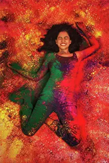 Holi Prints: High angle view of a indian teenage girl lying and covered in colored powder during holi color festival