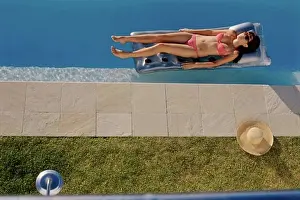 Sseditor Aa Prints: High angle view of a young woman lying on a pool raft
