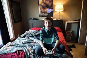 Gradeschooler Prints: High View of Teen Boy Gaming While Wearing Headset, Sitting on Bed