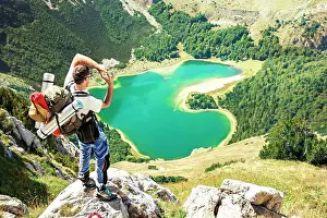 Backpacker Prints: Hiker standing on the rock, high above heart shaped lake in Montenegro