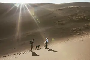 Sand Dunes Prints: two hikers and their dog follow footprints in the sand dunes