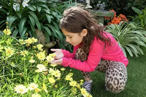 Gleeful Prints: Hispanic girl smelling yellow flowers in garden