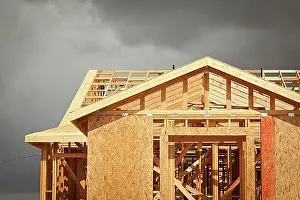 Projects Prints: Home construction framing with ominous grey clouds behind