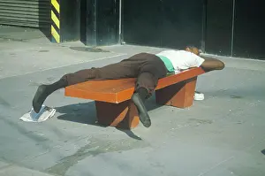 Poverty Prints: Homeless black man sleeping on a park bench, New York City, New York