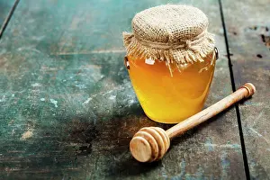 Still Life Prints: Honey jar and dipper on wooden background