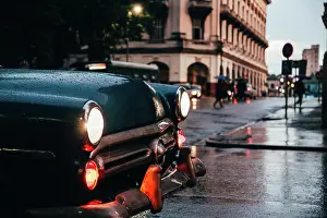 Hood Prints: Hood of blue vintage car with lights on and red old car in motion on background on rainy weather in Cuba