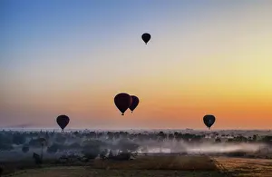 Weather Prints: Hot air balloons over landscape with distant temples at sunset, Bagan, Myanmar