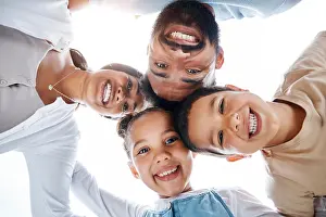 Huddled family bonding, laughing and having fun while standing in a circle with heads in the middle
