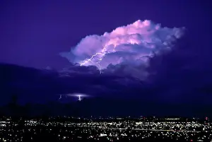 Flash Prints: Huge cumulonimbus cloud illuminated at twilight by pink alpenglow hues plus intracloud lightning