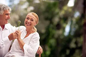 Baby Boomer Prints: Husband gives his wife a flower as they sit outdoors