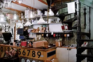 Self Employed Prints: Illuminated pendant lights hanging over checkout counter against various equipment at hardware store