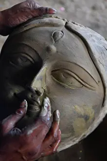 Tableware Prints: An Indian ceramic artists is sculpturing a clay face of Mother Goddess Durga at a studio