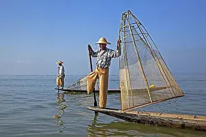 Ethnic Groups Prints: Two Intha fishermen steering traditional fishing boats by wrapping their leg around the oar