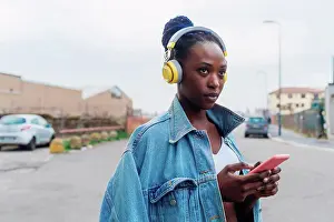 Using Phone Prints: Italy, Milan, Woman with headphones holding smart phone in city