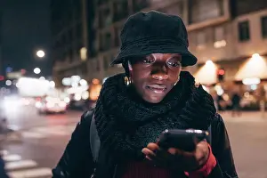 Using Phone Prints: Italy, Woman looking at smart phone in city at night