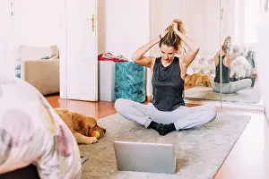 One Young Woman Only Prints: Italy, Young woman stretching in front of laptop on floor