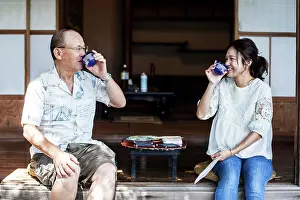 2people Prints: Japanese man and woman sitting on floor on porch of traditional Japanese house