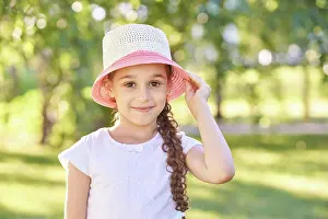 Gelassen Prints: Kaukasisches junges Mädchen mit Sommerhut lächelt im Freien im sonnenbeschienenen Park mit Caucasian young girl