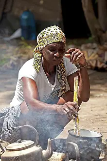 Prepare Prints: Kavango woman preparing the traditional Ugali maize flour dish on a campfire