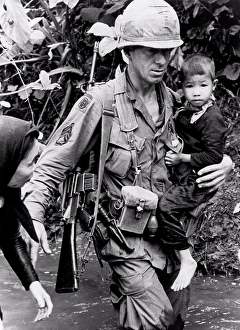 Threepeople Prints: An Khe, Vietnam: 1967 A member of the 1st Calvary Division helps a Vietnamese woman and her child across a stream