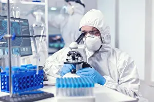 Technician Prints: Lab technician in ppe gear examining virus samples under microscope