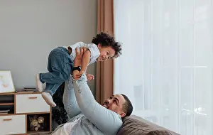 Mixed Prints: Lächelnder Vater, der seinen Sohn hochhebt