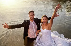 Lake, portrait of wet bride and groom standing in water together with excited smile and playful romance